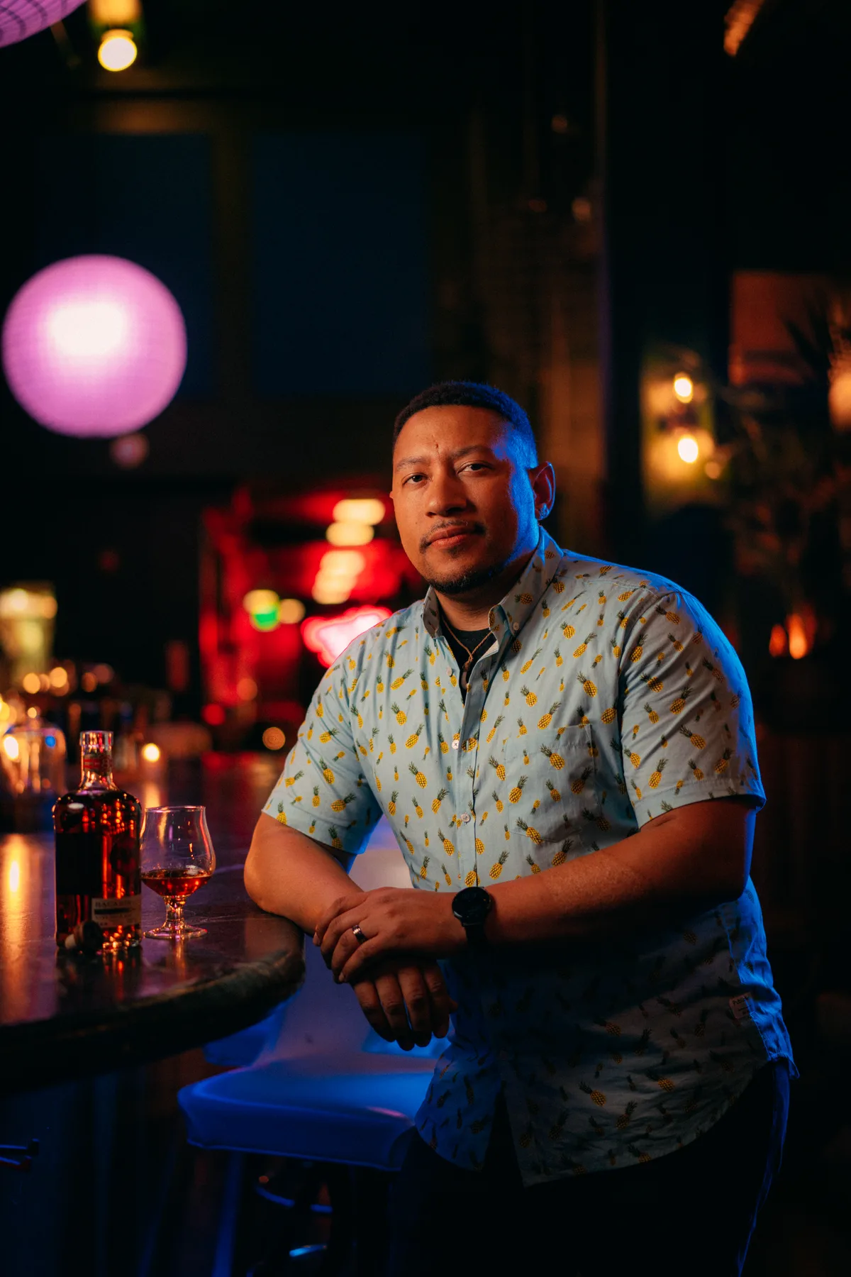 Chef Nelson German seated at the bar at Sobre Mesa, surrounded by colorful pendant lights
